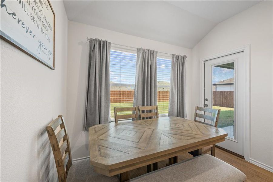 Dining area with healthy amount of natural light, vaulted ceiling, and wood finished floors Dining area with healthy amount of natural light, vaulted ceiling, and wood finished floors