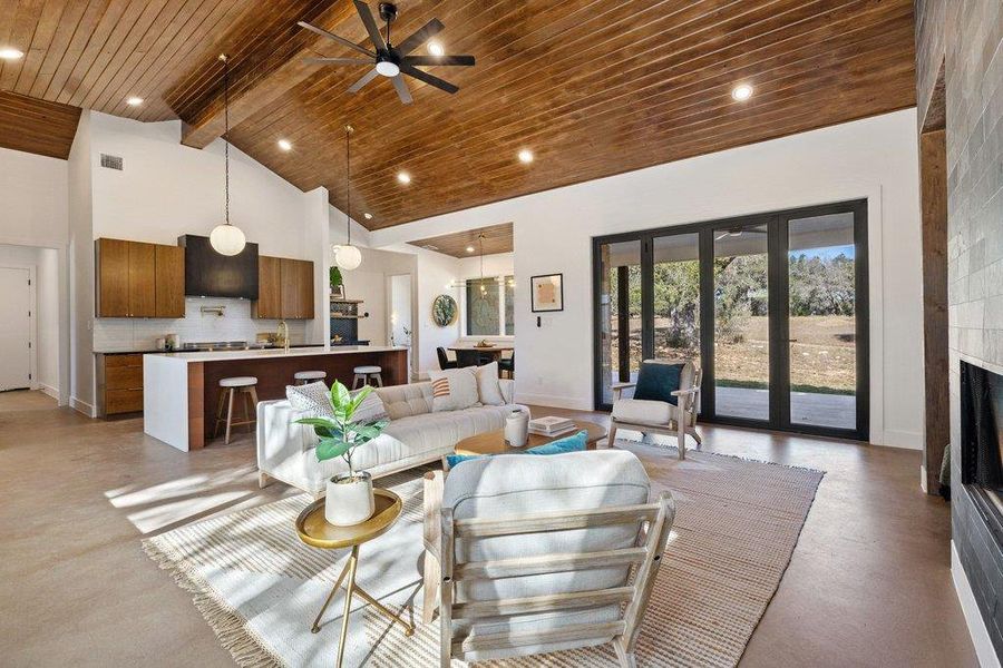 Living area featuring high vaulted ceiling, concrete floors, a large fireplace, a wooden ceiling with exposed beams, and ceiling fan