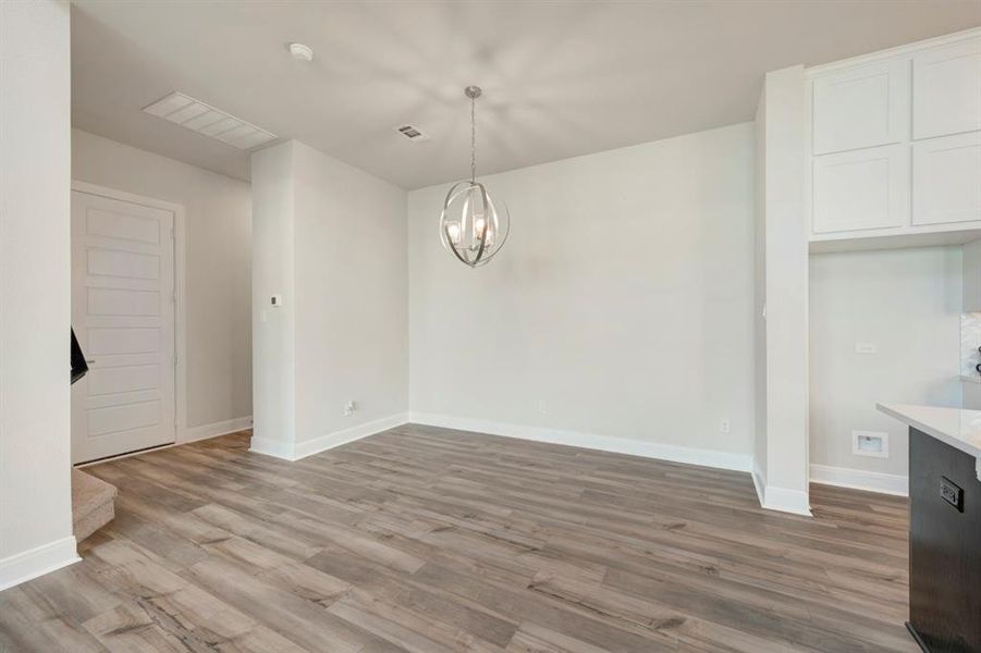 Unfurnished dining area with suspended lighting and dark wood-style flooring
