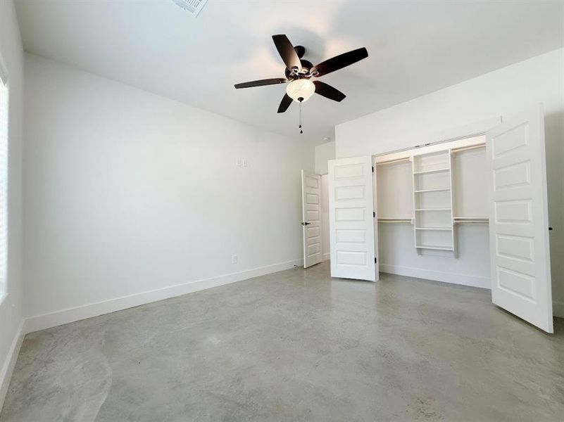 Unfurnished bedroom with concrete flooring, a ceiling fan, and a closet Unfurnished bedroom with concrete flooring, a ceiling fan, and a closet