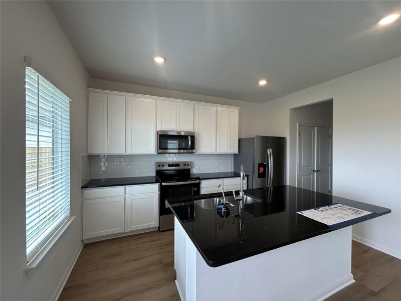 Kitchen featuring stainless steel appliances, dark wood-style floors, tasteful backsplash, dark countertops, and white cabinets