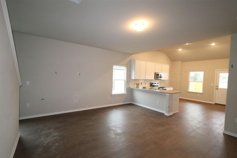 Kitchen featuring appliances with stainless steel finishes, white cabinets, kitchen peninsula, dark hardwood / wood-style flooring, and lofted ceiling