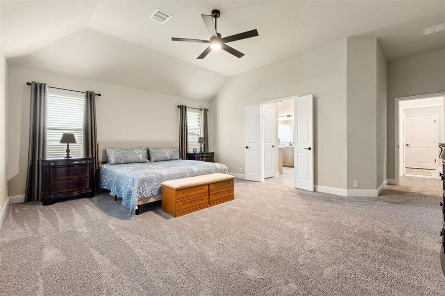 Vaulted ceiling room featuring light-toned walls, gray carpet flooring, and a ceiling fan Vaulted ceiling room featuring light-toned walls, gray carpet flooring, and a ceiling fan