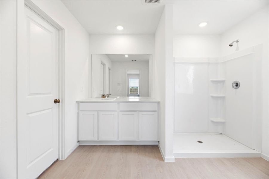 Primary bathroom includes a large vanity, oversized shower and a walk-in closet.