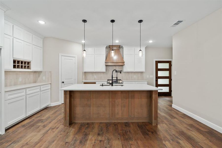 Kitchen with tasteful backsplash, white cabinetry, premium range hood, pendant lighting, and recessed lighting