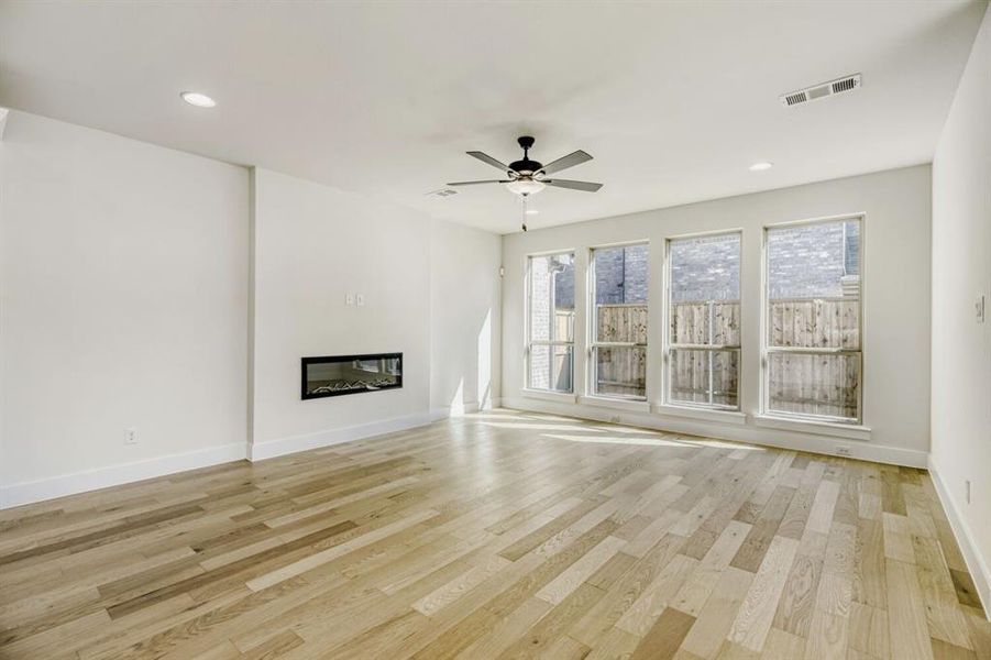 Unfurnished living room with ceiling fan, a glass covered fireplace, recessed lighting, and light wood-type flooring