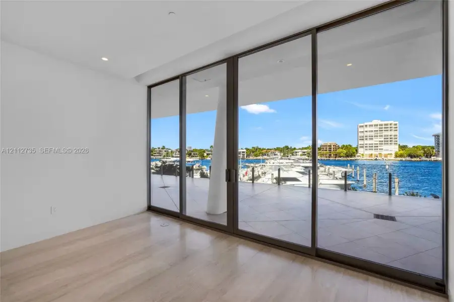 Floor-to-ceiling multi-panel sliding glass doors, wood-finish flooring, recessed lighting, and large format tiled balcony