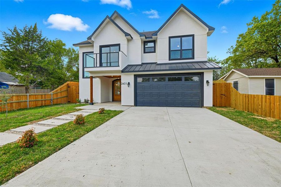 Modern farmhouse style home with a balcony, a standing seam roof, stucco siding, and an attached garage