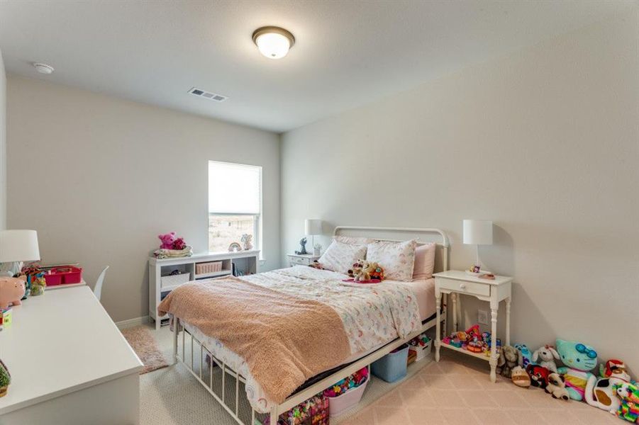 Bedroom featuring light carpet, baseboards, and visible vents