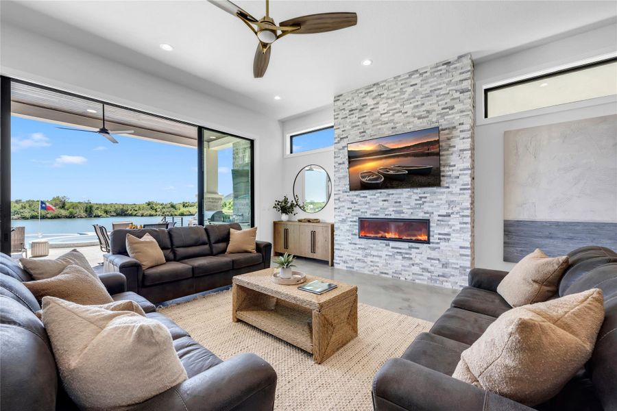 Living room one: A stone fireplace anchors the living room beside sliding glass doors revealing waterfront views.