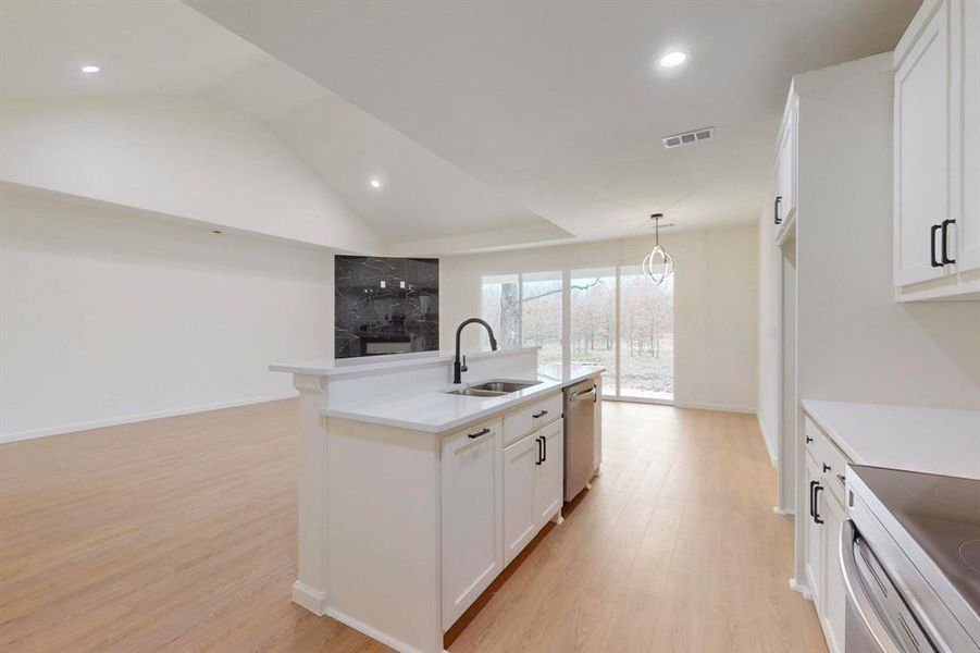 Kitchen featuring stainless steel dishwasher, light wood-type flooring, white cabinetry, and a sink