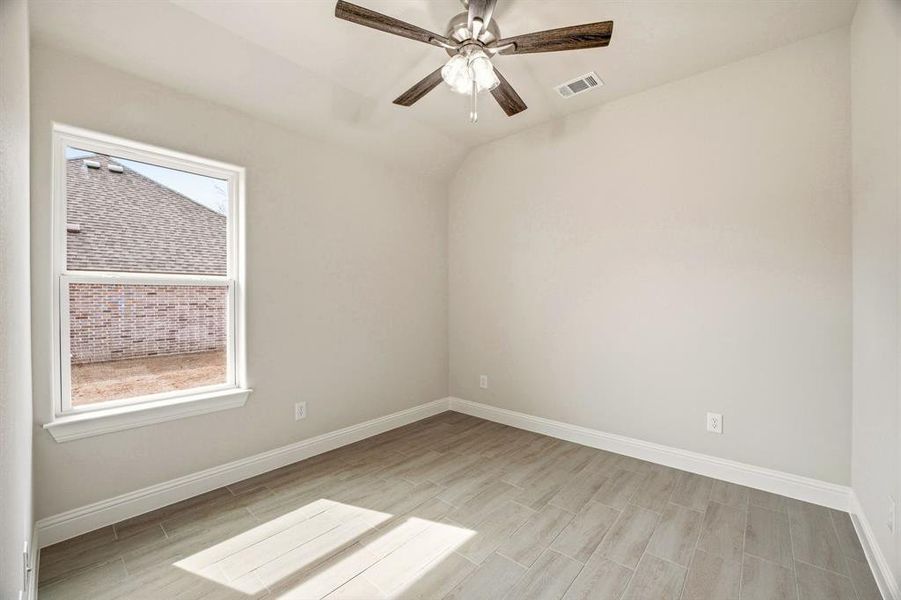 Empty room with ceiling fan, vaulted ceiling, and wood tiled floors