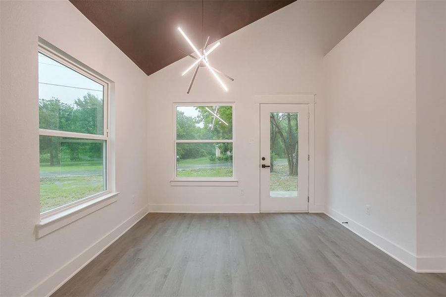 Spare room with healthy amount of natural light, wood finished floors, and vaulted ceiling