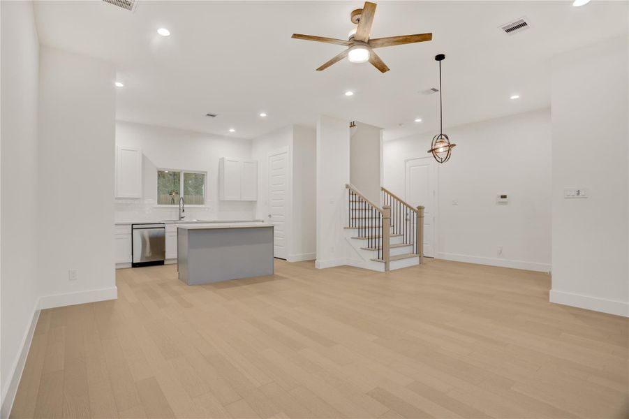 Open-concept living area with light flooring, modern lighting, and seamless flow to the kitchen.