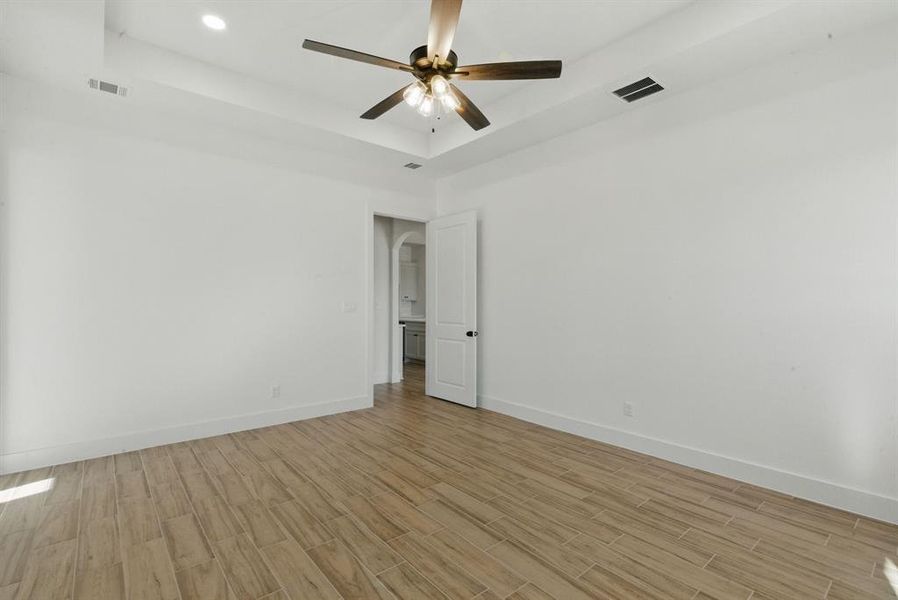 Unfurnished room featuring a raised ceiling, wood finish floors, recessed lighting, and a ceiling fan Unfurnished room featuring a raised ceiling, wood finish floors, recessed lighting, and a ceiling fan