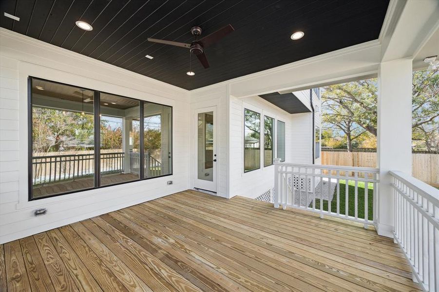 Expansive back porch is designed for both relaxation and entertainment, featuring a sleek black-paneled ceiling with recessed lighting and a ceiling fan for added comfort. The covered porch provides a seamless transition between indoor and outdoor living, making it the perfect spot for al fresco dining or morning coffee while enjoying the serene surroundings.