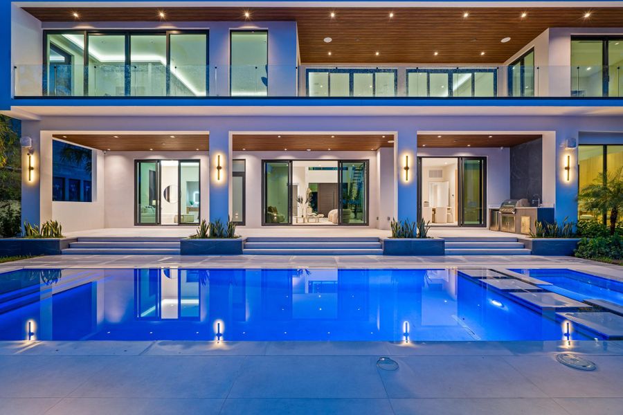 Sleek contemporary design with floor-to-ceiling glass doors opening to a glowing pool and expansive outdoor living spaces. Sleek contemporary design with floor-to-ceiling glass doors opening to a glowing pool and expansive outdoor living spaces.