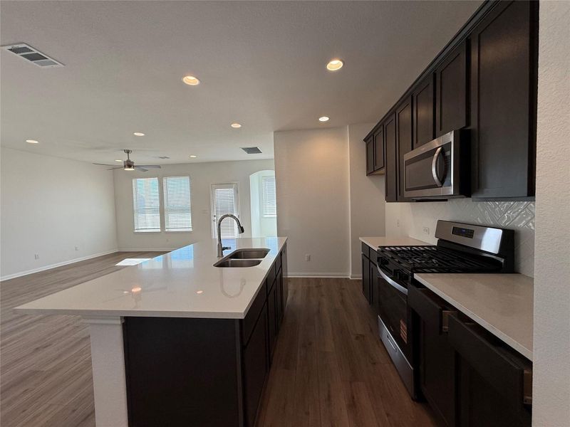 Kitchen featuring stainless steel appliances, recessed lighting, open floor plan, light stone counters, and dark wood finished floors Kitchen featuring stainless steel appliances, recessed lighting, open floor plan, light stone counters, and dark wood finished floors