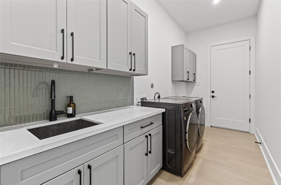Dedicated utility room offers extensive cabinetry, counter space, a sink, and room for full-size laundry appliances. **Images are from a previously completed project. **
