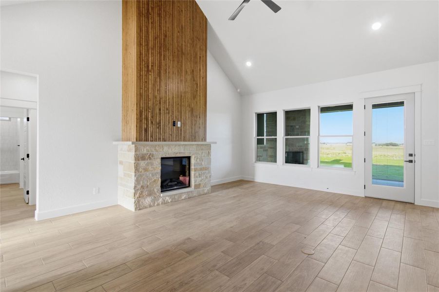 A spacious living area features high ceilings, a contemporary stone fireplace, and abundant natural light from large windows and a glass-paneled door. A spacious living area features high ceilings, a contemporary stone fireplace, and abundant natural light from large windows and a glass-paneled door.