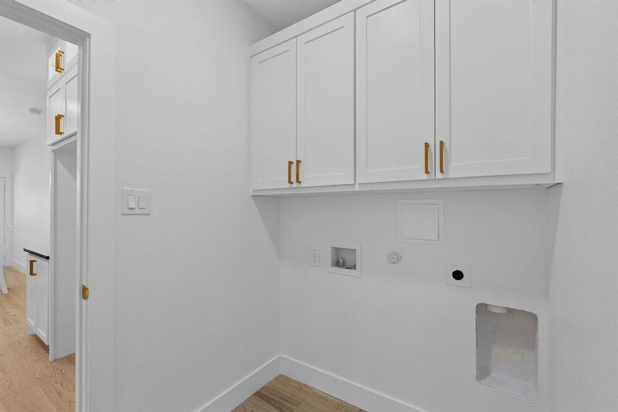 Dedicated laundry area featuring white shaker-style cabinetry with gold-tone hardware, providing ample storage
