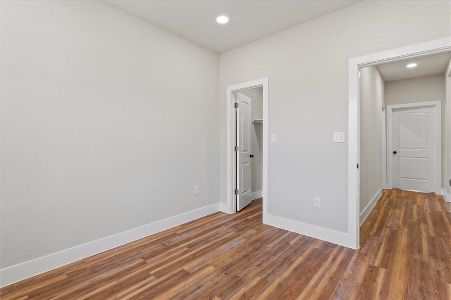 Unfurnished bedroom with a walk in closet, dark wood-type flooring, and recessed lighting