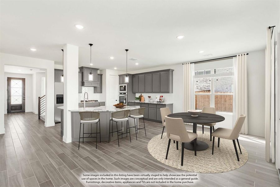 Open-concept kitchen and dining area with gray cabinets, island with bar seating, and round dining table near large window Open-concept kitchen and dining area with gray cabinets, island with bar seating, and round dining table near large window