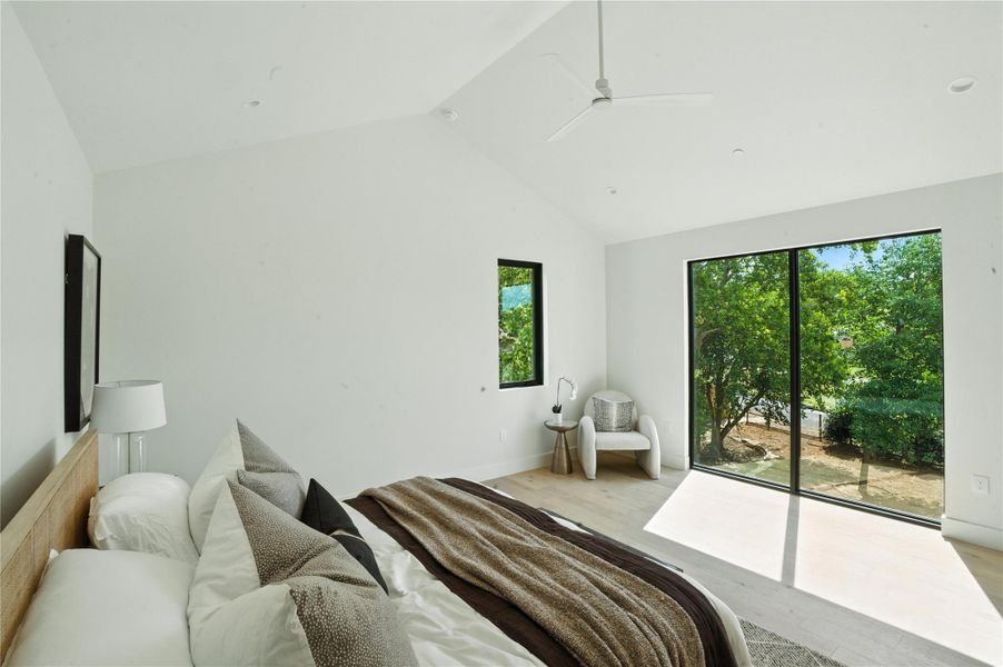 Bedroom featuring light wood-style flooring, access to outside, a ceiling fan, and high vaulted ceiling Bedroom featuring light wood-style flooring, access to outside, a ceiling fan, and high vaulted ceiling