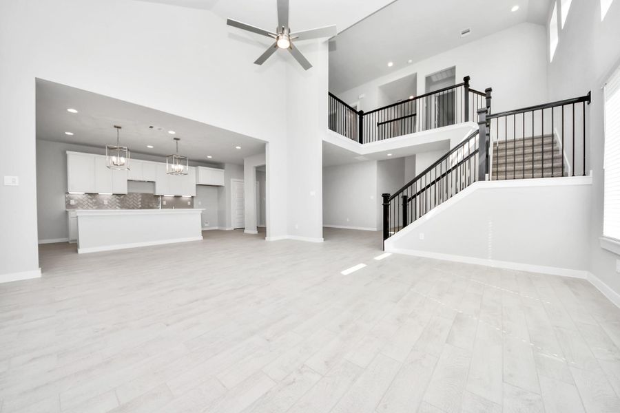 Relax and unwind in this inviting family room, illuminated by abundant natural light streaming in through tall windows, complemented by high ceilings and stunning flooring. Stay comfortable year-round with the gentle breeze from the ceiling fan, creating the perfect atmosphere for family gatherings. Sample photo of completed home with similar floor plan. Actual colors and selections may vary.