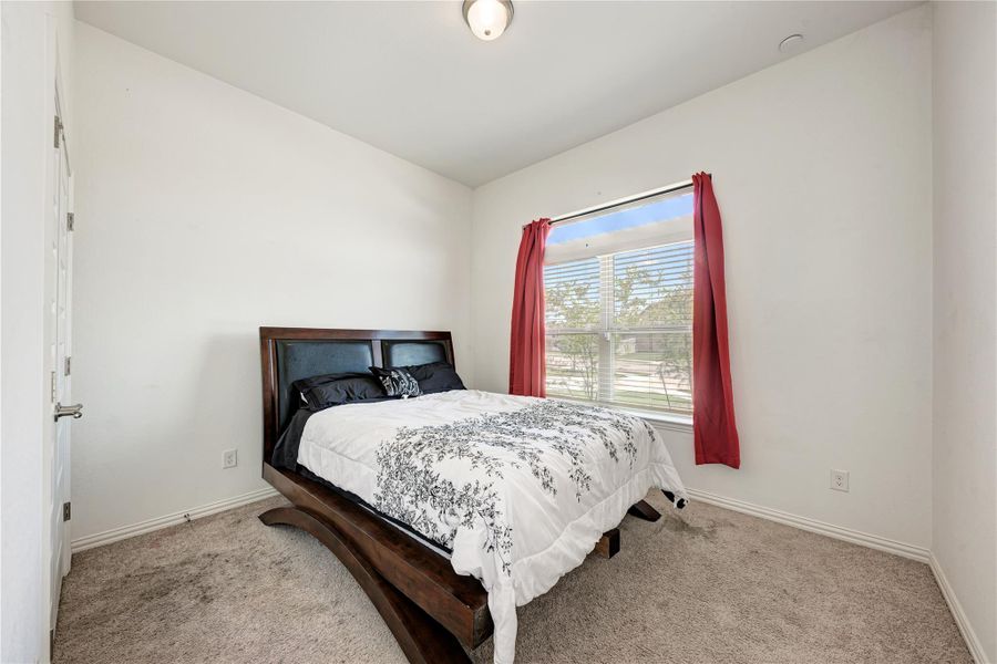 A quiet retreat, this bedroom offers carpeted flooring and a bright window.
