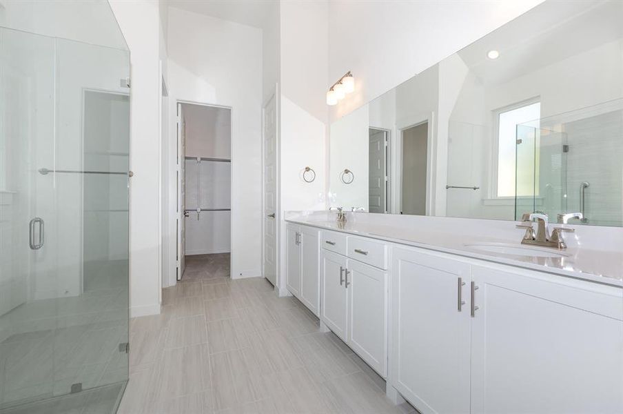 Bathroom featuring a shower stall, double vanity, and a spacious closet Bathroom featuring a shower stall, double vanity, and a spacious closet