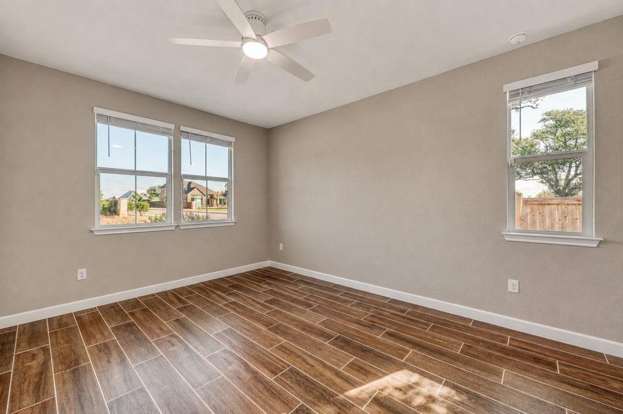 Rich wood-look tile flooring and clean baseboards anchor this versatile bedroom filled with natural light. Rich wood-look tile flooring and clean baseboards anchor this versatile bedroom filled with natural light.