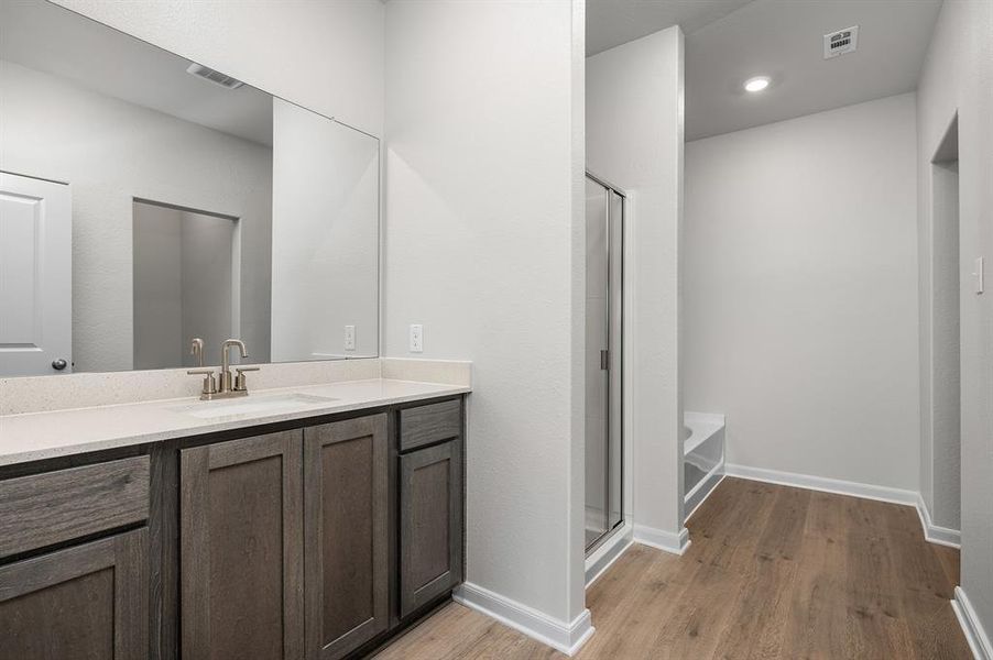 Full bath featuring light wood-style floors, vanity, a stall shower, a tub, and recessed lighting