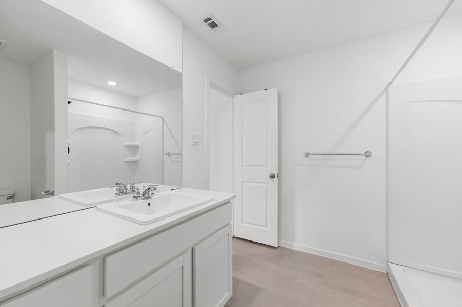 Alternate view highlights the generous vanity counter, oversized mirror, neutral finishes, and walk-in shower. Alternate view highlights the generous vanity counter, oversized mirror, neutral finishes, and walk-in shower.