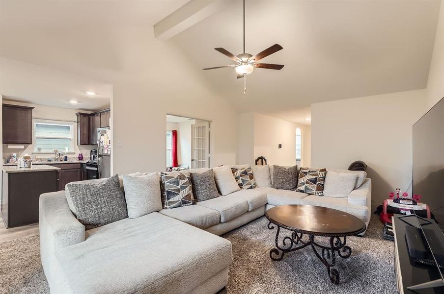 Living room with beam ceiling, ceiling fan, high vaulted ceiling, and hardwood / wood-style flooring