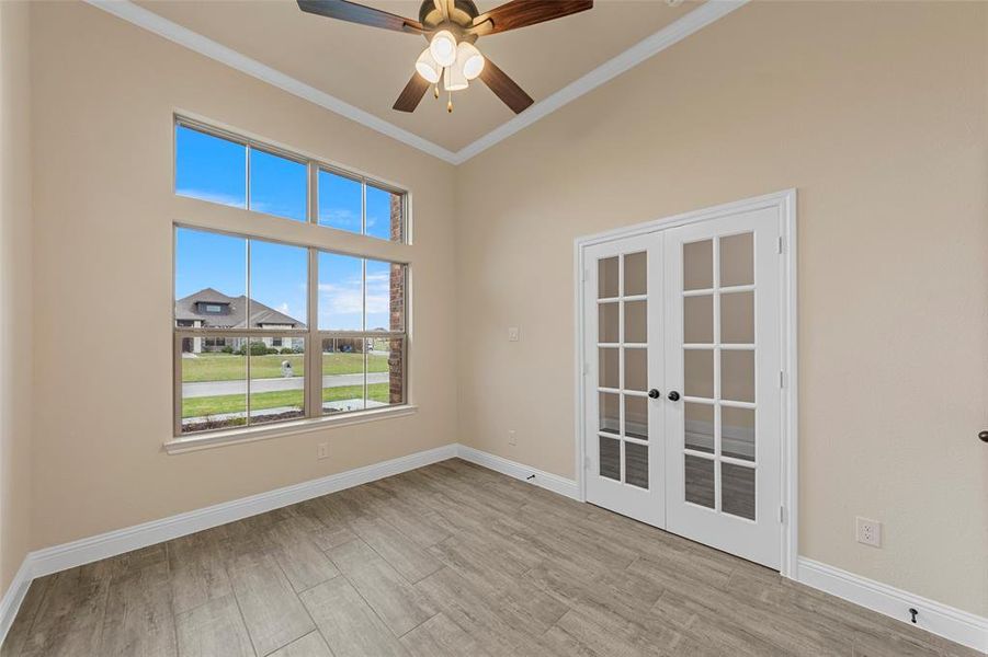 Empty room featuring french doors, plenty of natural light, ornamental molding, a ceiling fan, and wood finished floors