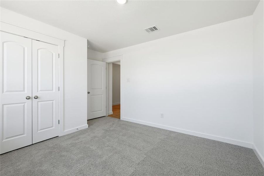 Unfurnished bedroom with light colored carpet and a closet