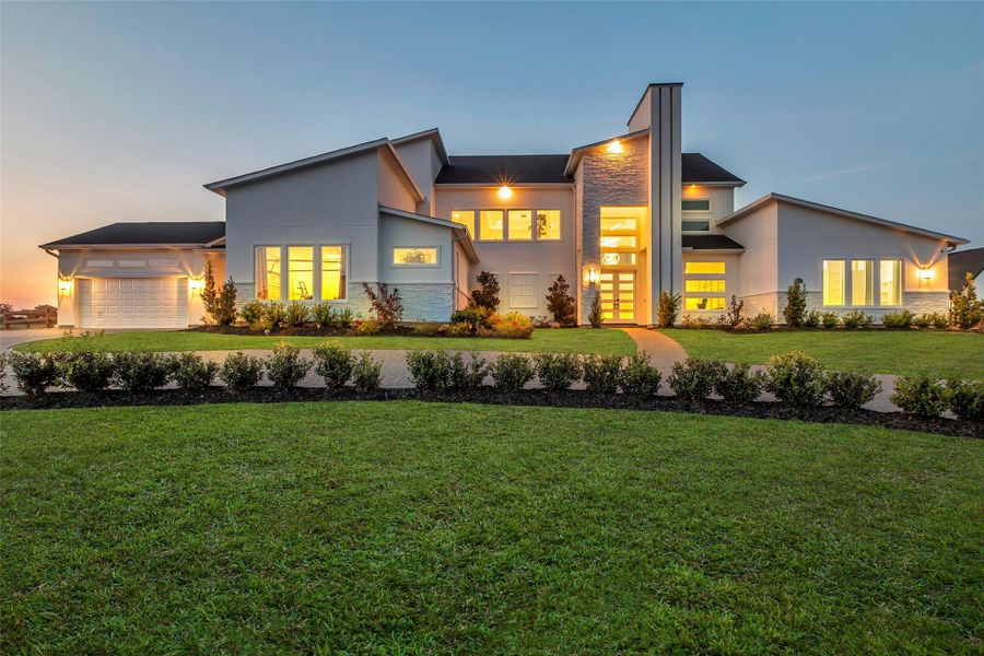 Architectural Presence: At twilight, the residence makes a commanding statement with its contemporary façade, soaring rooflines, and luminous walls of glass. Clean architectural lines blend with curated landscaping to frame a dramatic entry, while uplighting and expansive windows showcase the home’s scale and sophistication from the very first impression.