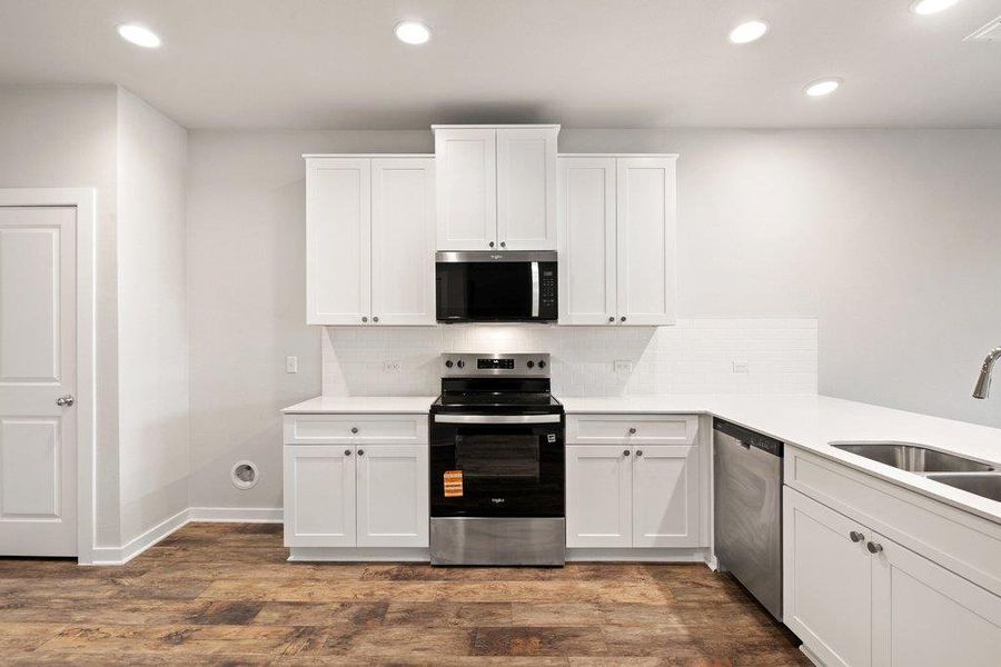 Kitchen featuring stainless steel appliances, recessed lighting, white cabinets, and backsplash