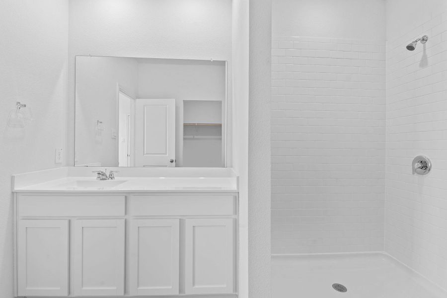 Bathroom featuring a tile shower and vanity