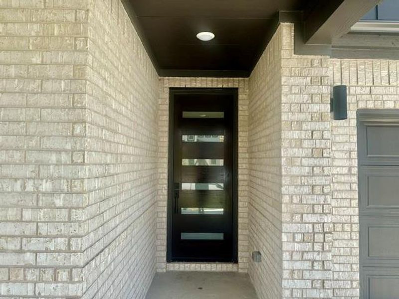 A contemporary entry features a sleek dark door with frosted glass accents, complementing the light-colored brick exterior. A contemporary entry features a sleek dark door with frosted glass accents, complementing the light-colored brick exterior.