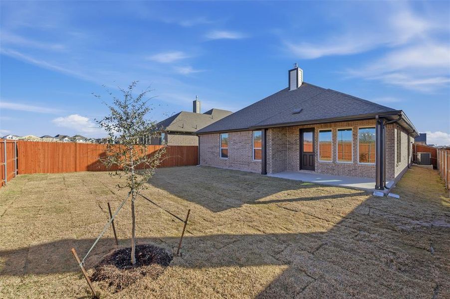 Back of property featuring brick siding, a fenced backyard, a patio area, roof with shingles, and a chimney