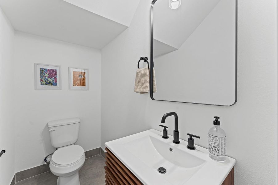 Tucked conveniently near the living area, this powder room blends accessibility with sleek contemporary style. Clean lines and modern fixtures define the space, from the minimalist vanity to the streamlined sink and faucet.
