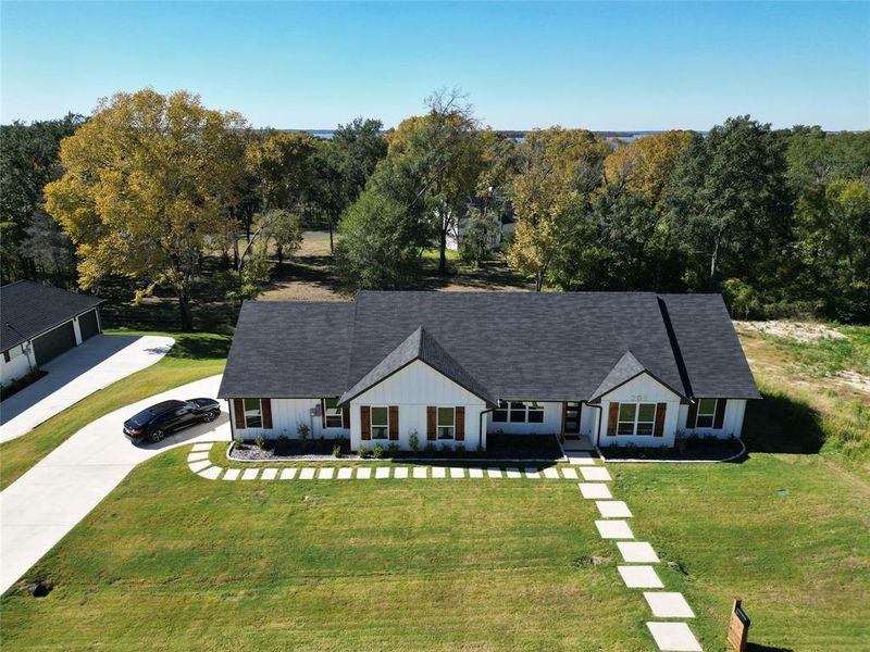 View of front of property with a front yard, a shingled roof, board and batten siding, and concrete driveway