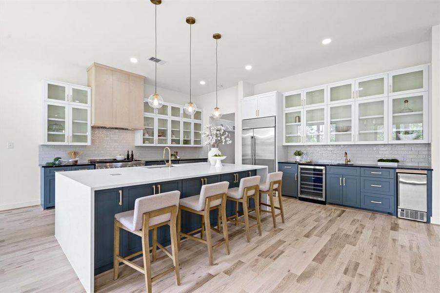 Stunning kitchen featuring oak floors, custom cabinets, a quartz island with seating. Beverage area with secondary prep sink, wine cooler, and built-in ice maker.