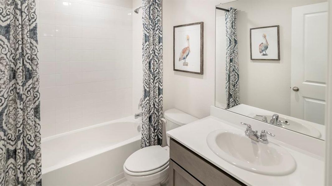 Bathroom featuring a white bathtub with subway tile surround, a toilet, and a vanity with a white countertop and oval sink