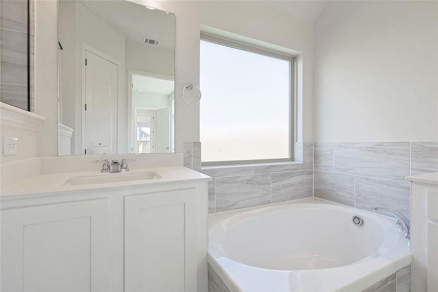 Bathroom featuring vanity and tiled bath