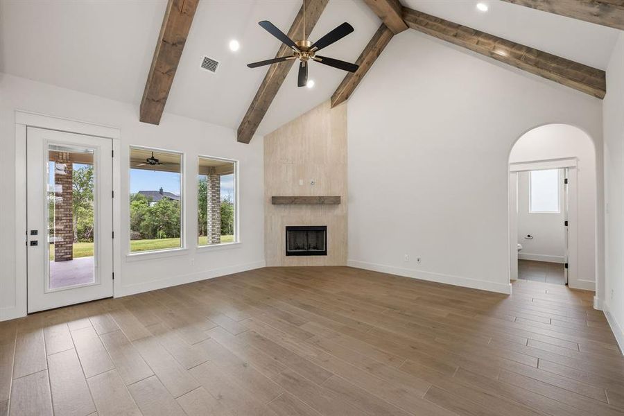 Spacious living area featuring a vaulted ceiling with exposed wood beams, a ceiling fan, and recessed lighting
