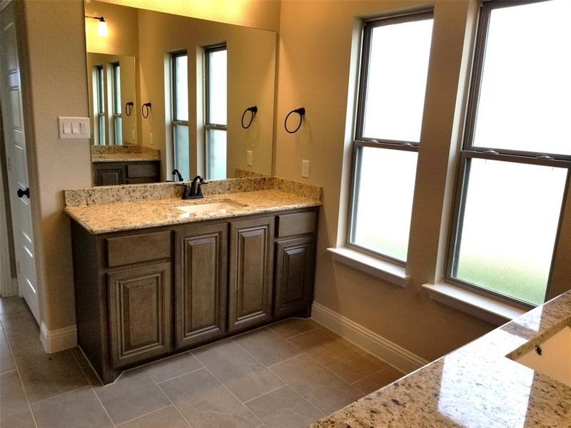 Master bath features separate granite vanities, garden tub, and separate shower with frameless glass