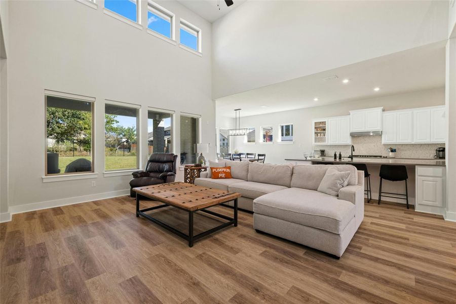 Living area with wood finished floors, a high ceiling, and recessed lighting Living area with wood finished floors, a high ceiling, and recessed lighting